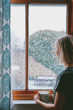 Woman staring out a window at rain